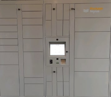 Stone-gray Parcel Locker Wall With Mixed Compartment Sizes And a Kiosk Screen In a Corporate Interior.