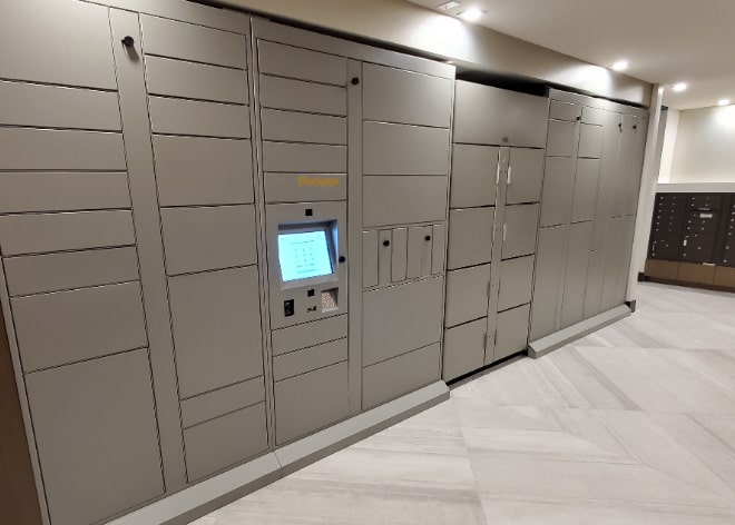 Package Nexus indoor smart parcel locker bank with central touchscreen in a multifamily delivery area. | Package Nexus